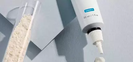 A tube of SkinCeuticals Retinol 0.3 cream is shown next to a small glass container with white powder, with three dabs of the cream on a light-colored surface.