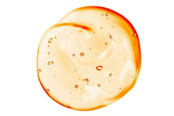 Une substance brillante et translucide formant une tache circulaire avec une teinte orange et de petites bulles d'air.