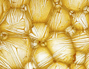 Image en gros plan de cristaux de sel brillants, montrant une texture doree et des motifs en relief.