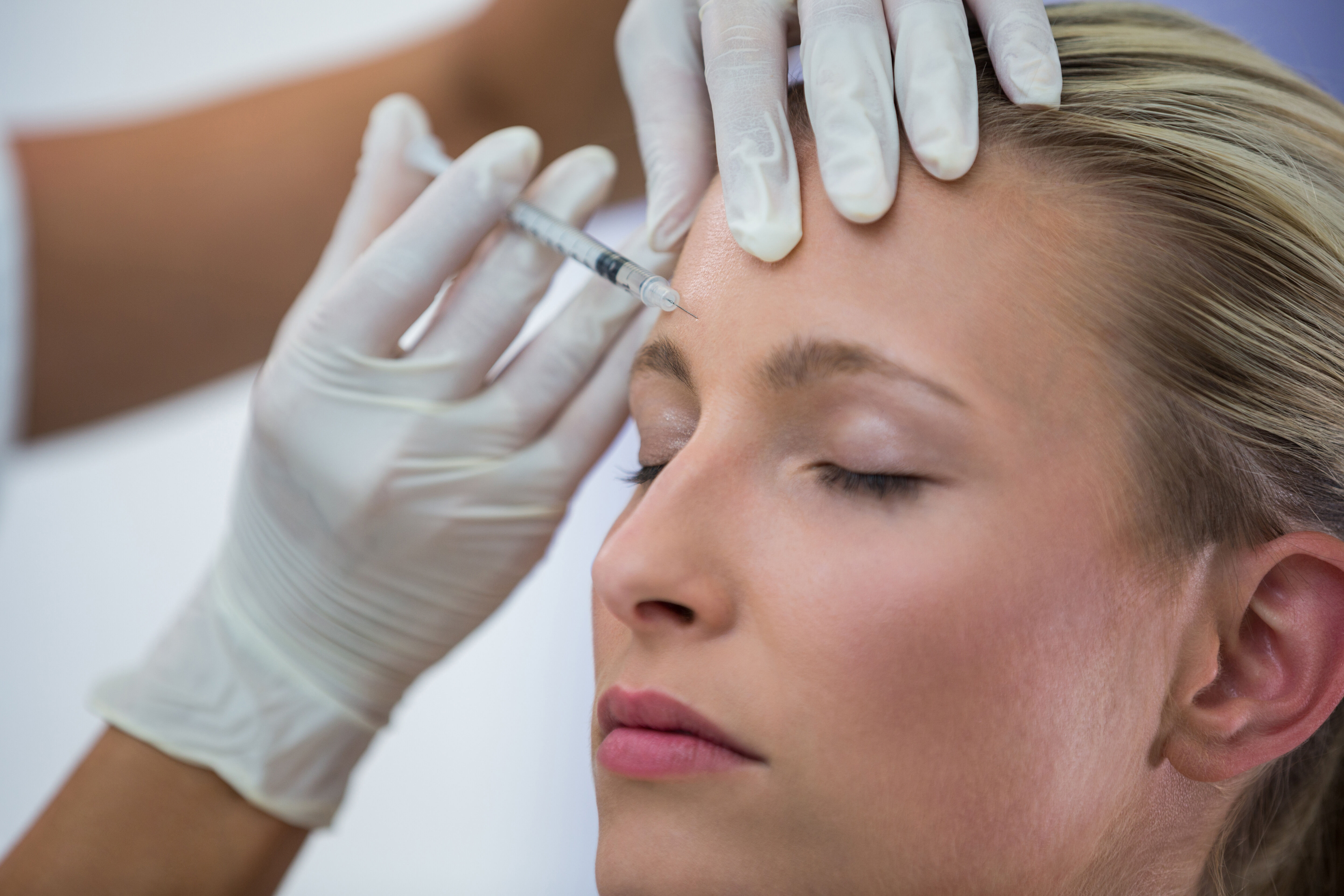 Une femme subit un traitement esthetique avec une injection dans le front.