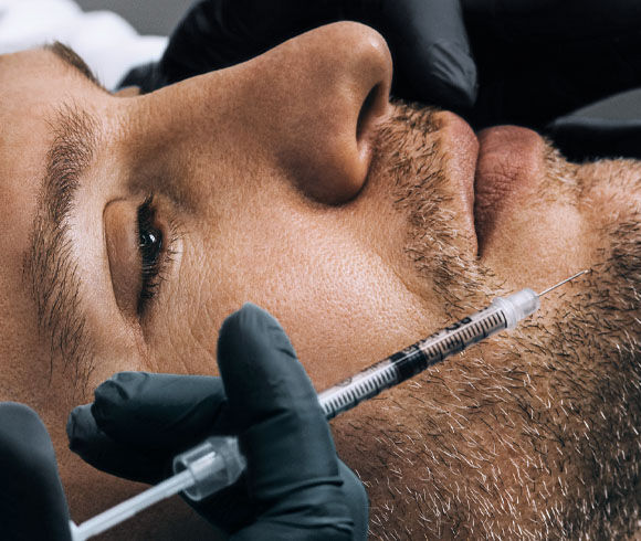Un gros plan d'un homme avec une seringue pres de son visage, tandis qu'une infirmiere realise la procedure.