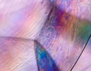 Abstracte close-up van een kleurrijke, iriserende textuur met golvende patronen en zachte overgangen.