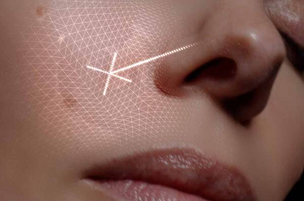 Un gros plan d'un visage avec un motif geometrique trace sur la peau, specialement autour du nez et des joues.
