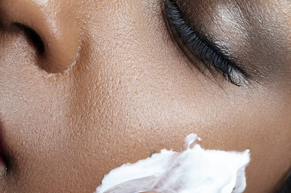 Gros plan d'une femme appliquant une creme visage sur son visage.