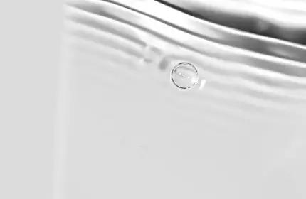 Abstract close-up of soft, flowing water with gentle ripples and bubbles on a light background.