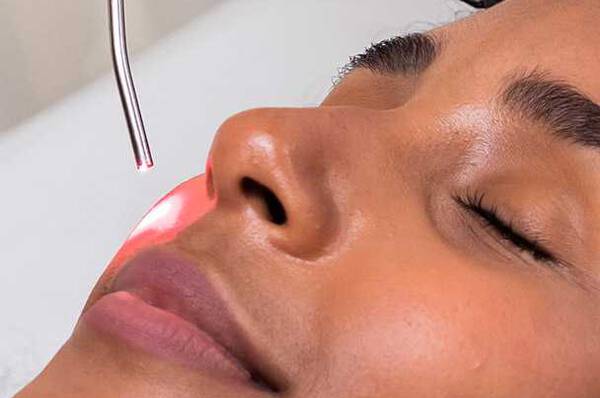 Femme aux yeux fermes subissant un traitement cutane avec un systeme laser.