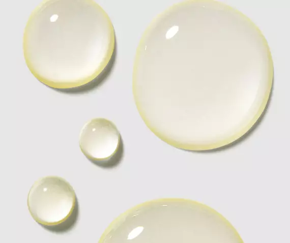 Drops of clear liquid in varying sizes, reflecting light against a soft gray background.
