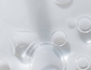 Duidelijke close-up van waterdruppels op een gladde, lichte ondergrond.