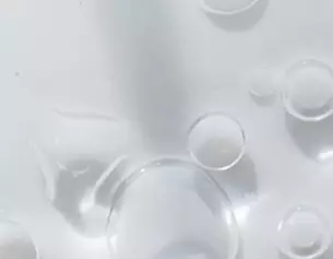 Bulles d'air flottant a la surface d'un liquide clair, creant une texture visuelle delicate.