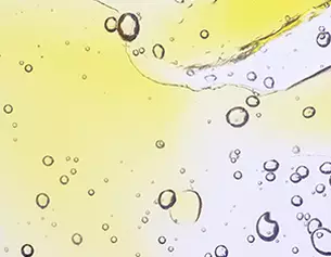 Bubbles rising in a translucent liquid with a gradient of yellow to clear, creating an abstract, fluid appearance.