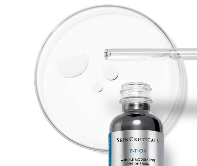 Flacon de serum SkinCeuticals P-TIOX avec des gouttes sur une plaque de Petri, mettant en avant sa texture.
