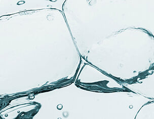 Close-up of ice cubes submerged in clear water, with bubbles rising and creating a refreshing, cool atmosphere.