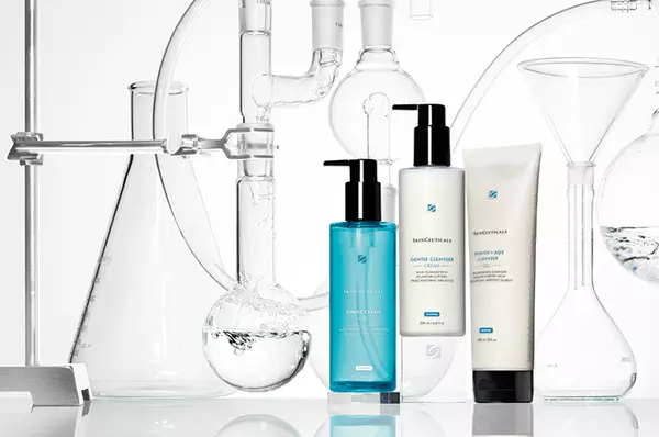 Trois flacons de nettoyants pour le visage sont places parmi de la verrerie de laboratoire contenant de l'eau et d'autres liquides.