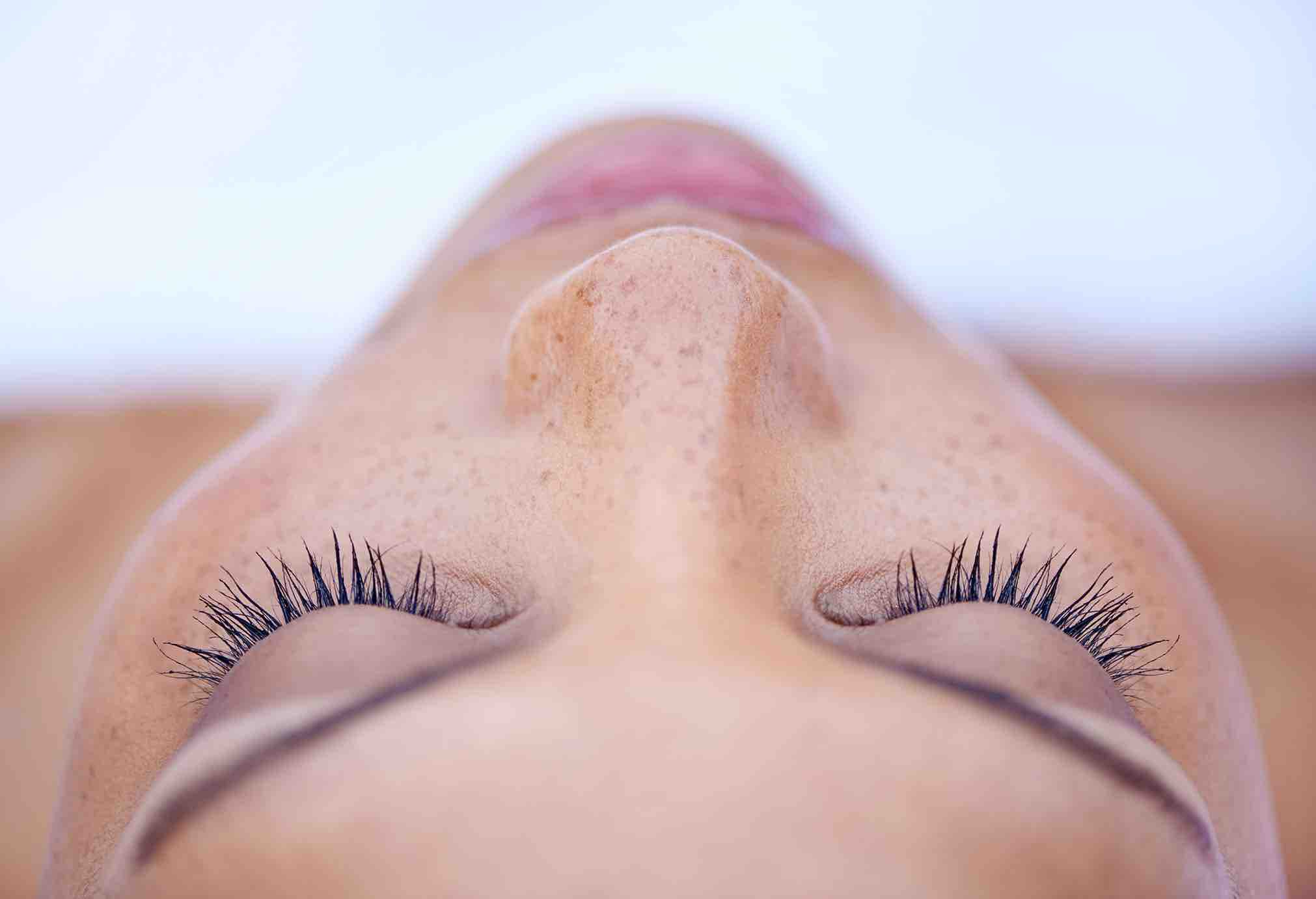 Een close-up van een vrouw met gesloten ogen, waarbij de focus ligt op haar wimpers en huid.