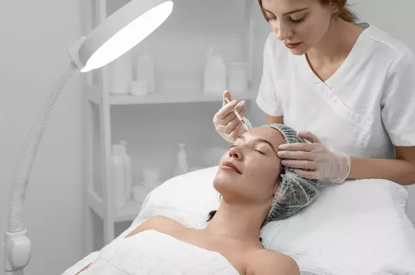 Une femme recoit un soin de la part d'une estheticienne dans un environnement spa moderne.