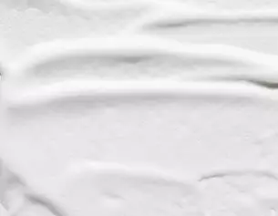 Close-up of smooth, white cream with soft, flowing texture and subtle ridges.