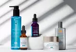 Produits de soin SkinCeuticals sur un fond clair avec des jeux d'ombres. Comprend un nettoyant, des serums et une creme solaire.