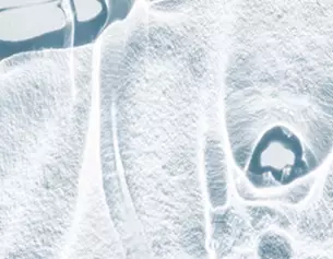 Close-up of an abstract, icy surface with intricate patterns and textures, resembling frost or frozen water.