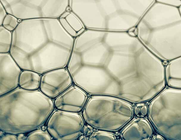 Des bulles de savon translucides formant un motif hexagonal complexe, capturant la lumiere avec douceur.