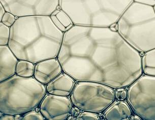 Des bulles de savon translucides formant un motif hexagonal complexe, capturant la lumiere avec douceur.
