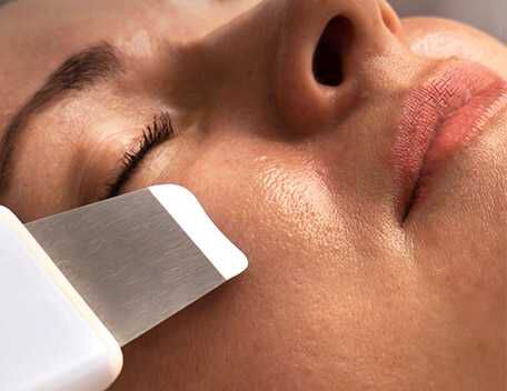 Un gros plan d'un visage sur lequel un appareil de soin de la peau est utilise. La peau parait lisse et eclatante.
