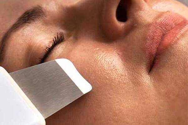 Un gros plan d'un visage sur lequel un appareil de soin de la peau est utilise. La peau parait lisse et eclatante.