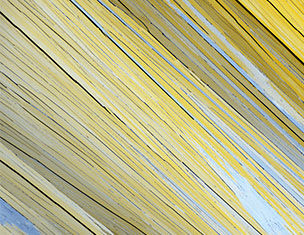 Close-up of textured yellow and gray wooden planks angled diagonally, creating a dynamic visual pattern.